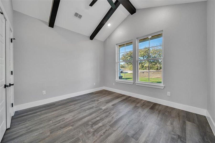 Empty room with wood-type flooring and lofted ceiling with beams