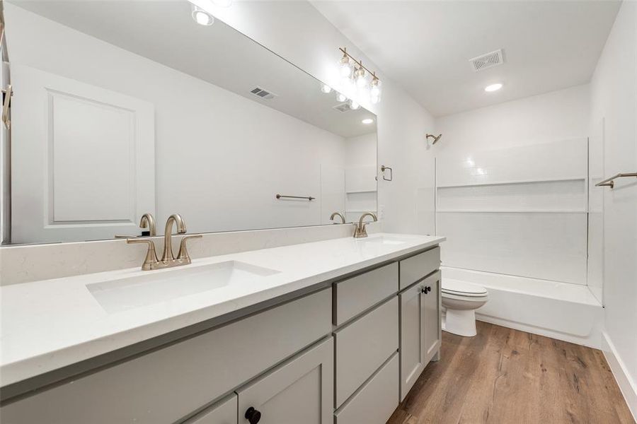 Full bathroom featuring wood-type flooring, vanity, shower / bathtub combination, and toilet