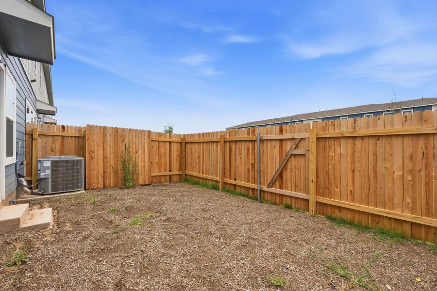 Fenced outdoor space featuring a wood privacy fence with a gate, a side exterior wall with siding, and an outdoor HVAC unit Fenced outdoor space featuring a wood privacy fence with a gate, a side exterior wall with siding, and an outdoor HVAC unit