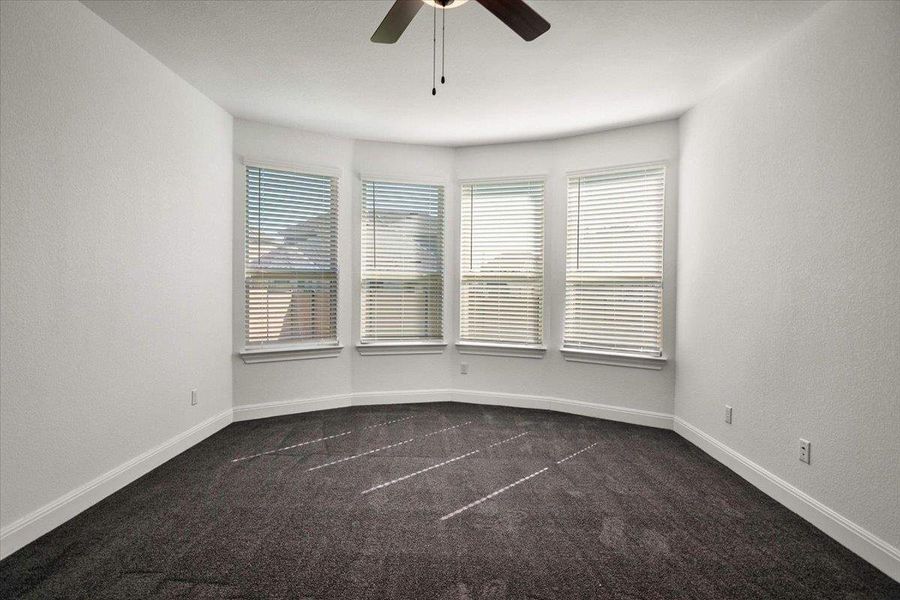 A well-lit bedroom offers bay windows and comfortable carpeting.