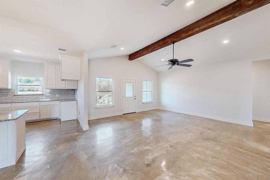 Unfurnished living room with lofted ceiling with beams and ceiling fan