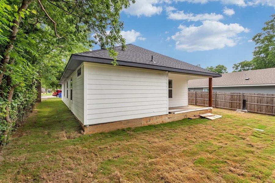 Back of house with a spacious fenced in lawn