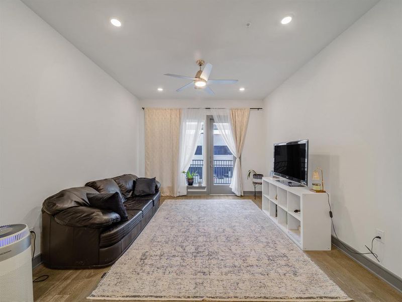 Living area with light wood-style flooring, ceiling fan, and recessed lighting