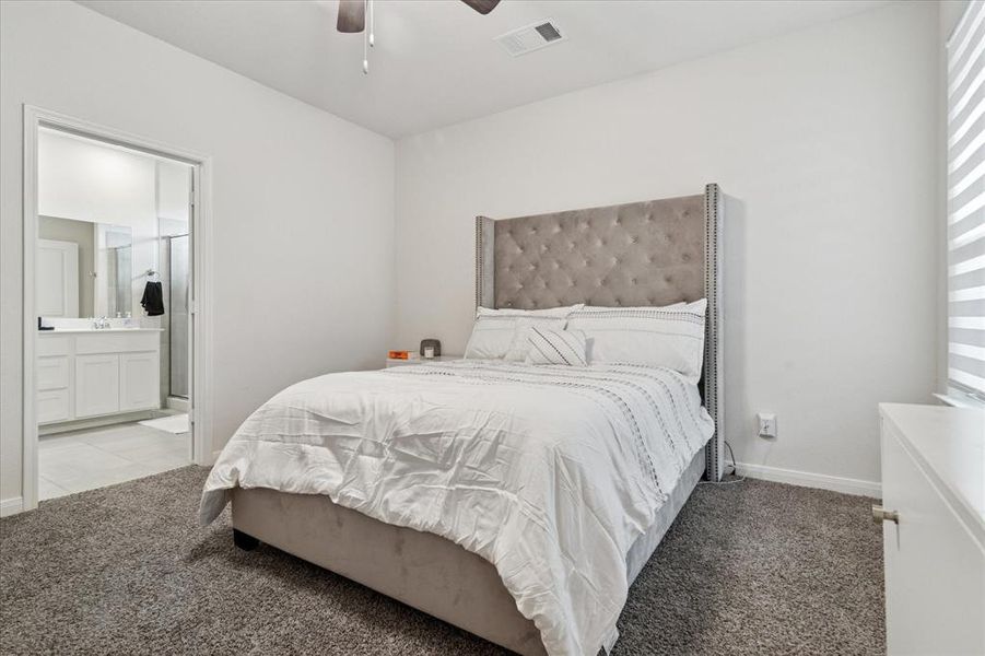 Bedroom featuring light carpet, ceiling fan, and connected bathroom Bedroom featuring light carpet, ceiling fan, and connected bathroom