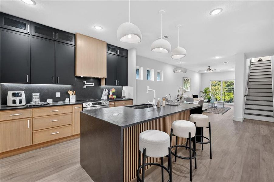 Open-concept kitchen featuring two-tone cabinetry, stone countertops, and an expansive island with a built-in sink