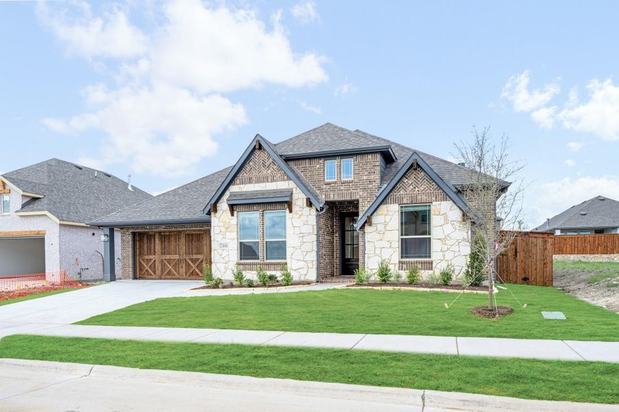 Single-story home with brick and stone exterior, wood garage door, and manicured front lawn