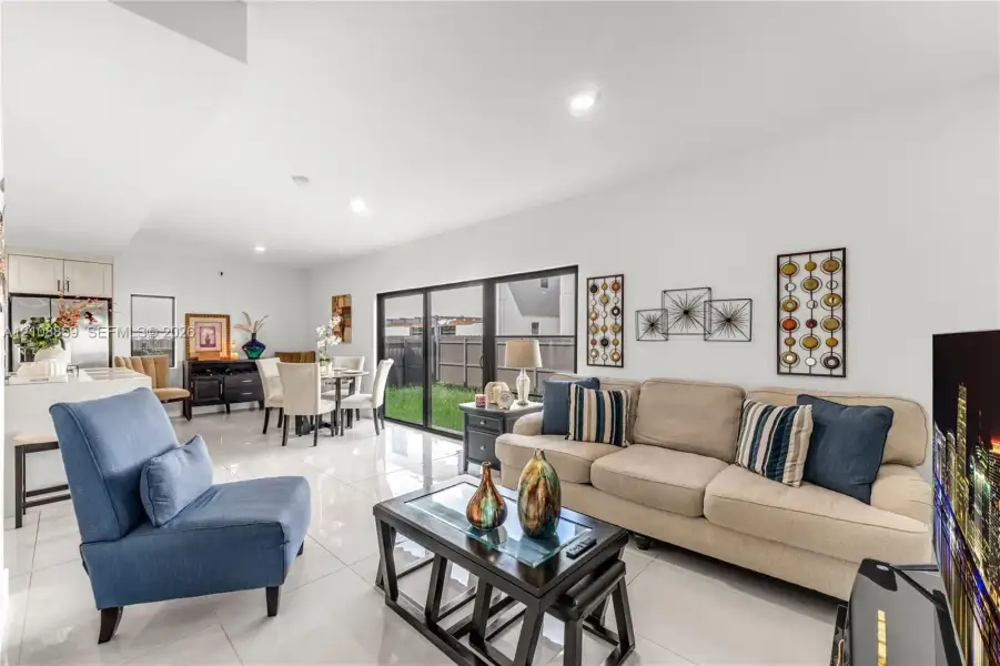 Open-concept interior featuring large-format tile flooring, recessed lighting, and expansive glass sliding doors