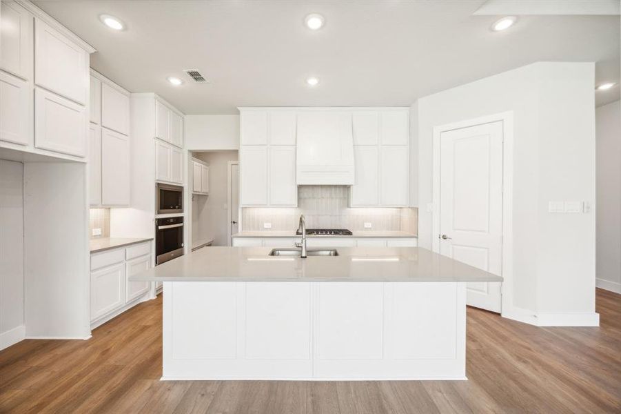 Kitchen featuring a center island with sink, stainless steel appliances, and light hardwood / wood-style flooring