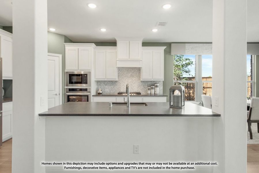 Kitchen with white cabinets, herringbone tile backsplash, gray island countertop, and stainless steel appliances Kitchen with white cabinets, herringbone tile backsplash, gray island countertop, and stainless steel appliances