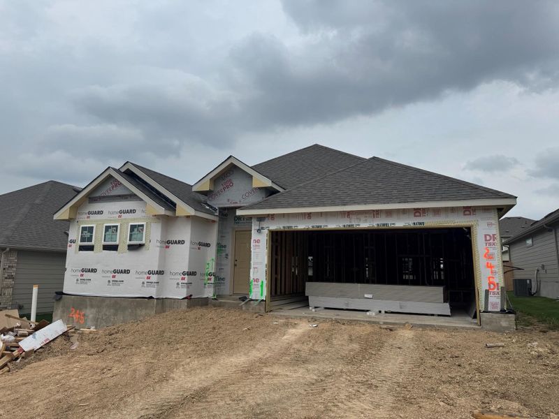 Property in mid-construction with a shingled roof, an attached garage, driveway, and central air condition unit Property in mid-construction with a shingled roof, an attached garage, driveway, and central air condition unit