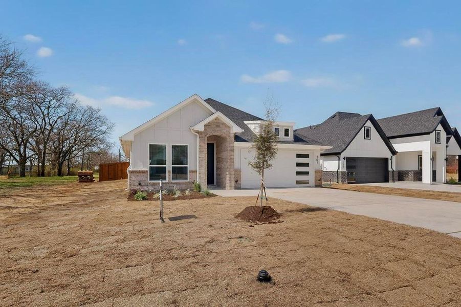 View of front of house featuring concrete driveway, an attached garage, brick siding, and board and batten siding View of front of house featuring concrete driveway, an attached garage, brick siding, and board and batten siding