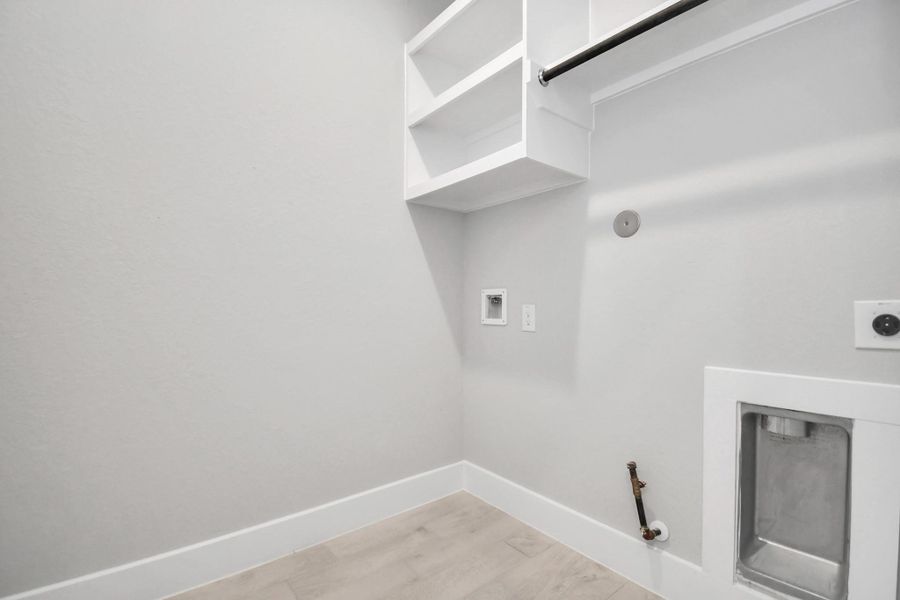 A perfect blend of functionality and comfort. Capture the essence of easy living with a first-floor laundry room, thoughtfully equipped with shelving for effortless organization. Both electric and gas connections available. Sample photo of completed home with similar floor plan. Actual colors and selections may vary.