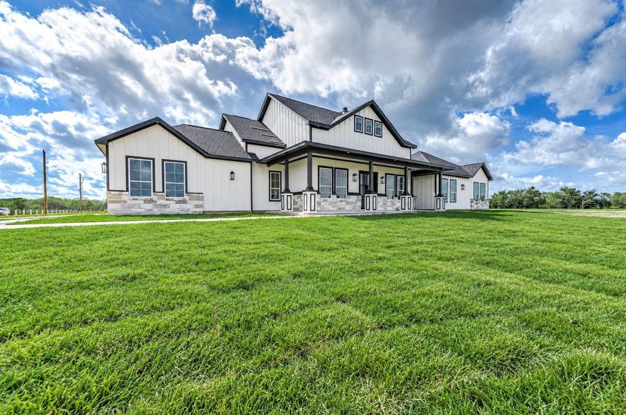 Another view of the home showcasing the covered front porch, spacious yard, and beautiful exterior details.