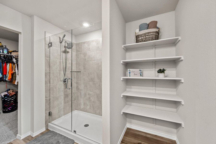 A well-appointed shower stall featuring tile surround and a glass enclosure, complemented by convenient open shelving.