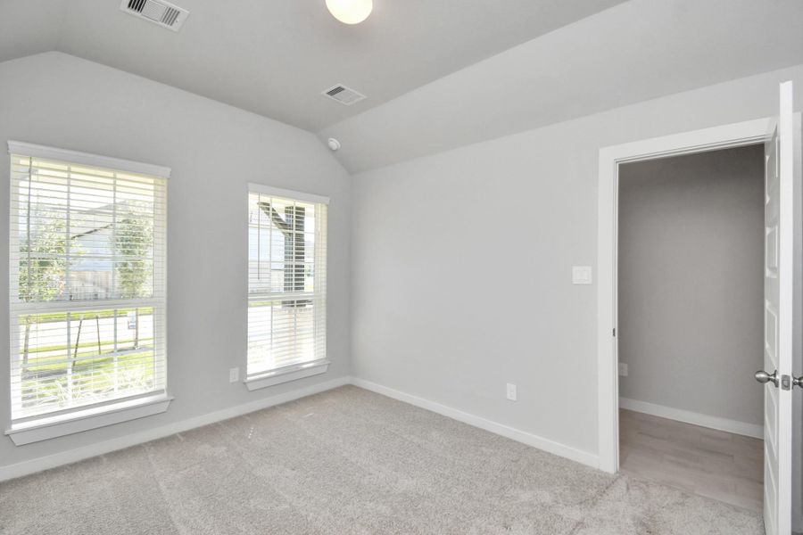 Secondary bedroom features plush carpeting, large windows that let in plenty of natural light, bright paint, and spacious closets. Sample photo of completed home with similar floor plan. Actual colors and selections may vary.