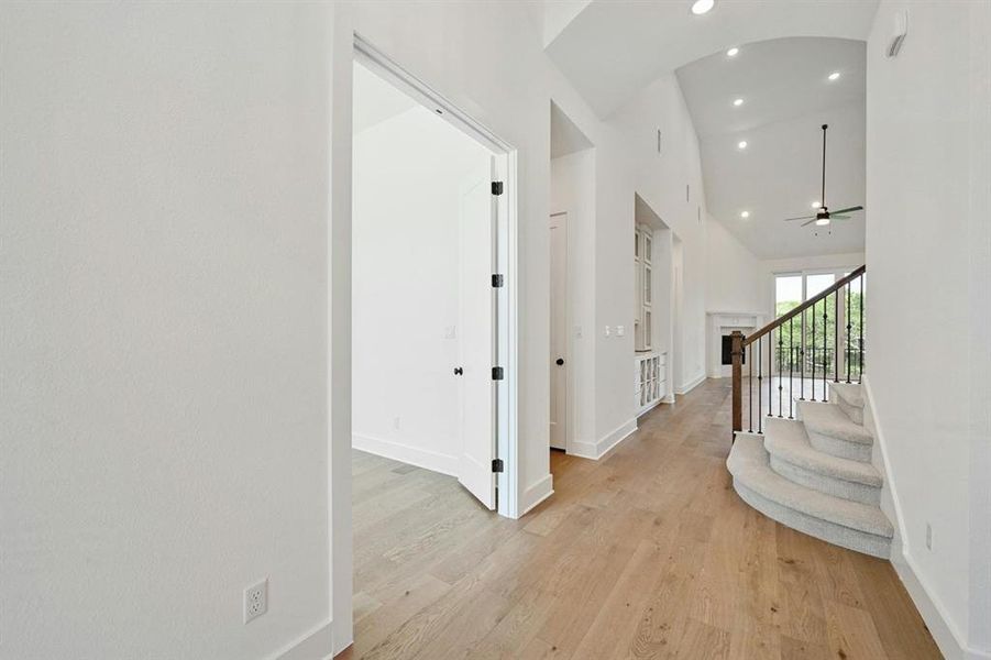 Corridor with recessed lighting, light wood-type flooring, stairway, and high vaulted ceiling Corridor with recessed lighting, light wood-type flooring, stairway, and high vaulted ceiling