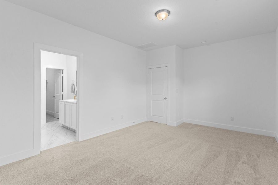 Another view of the inviting primary suite shows its open layout leading to the luxurious primary bathroom. This relaxing space offers plenty of room for your favorite furniture pieces while maintaining an airy, peaceful vibe. **Image Representative of Plan Only and May Vary as Built**.