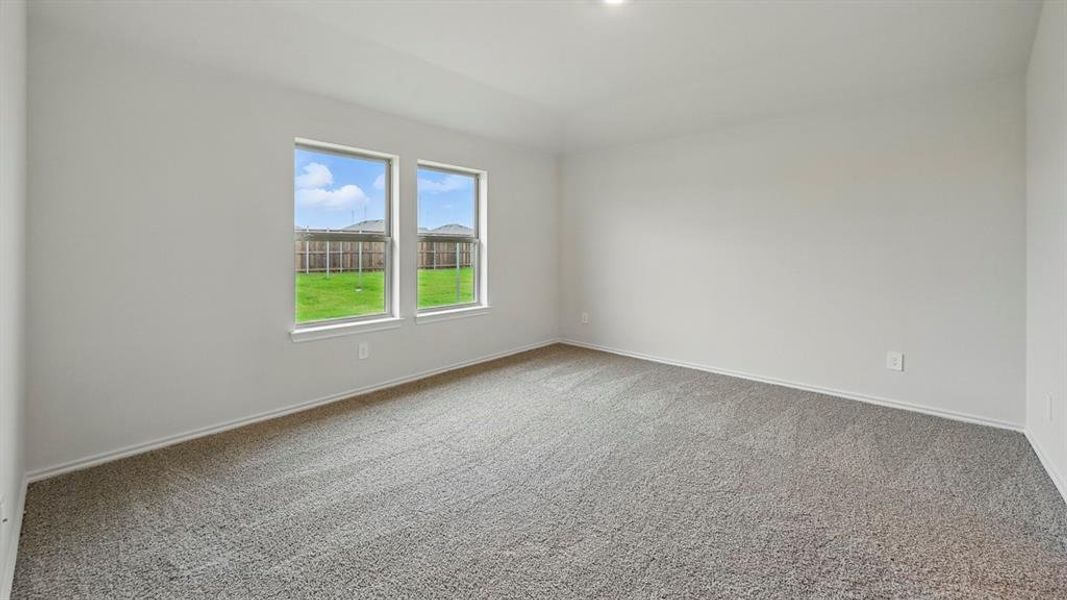 Carpeted spare room featuring baseboards