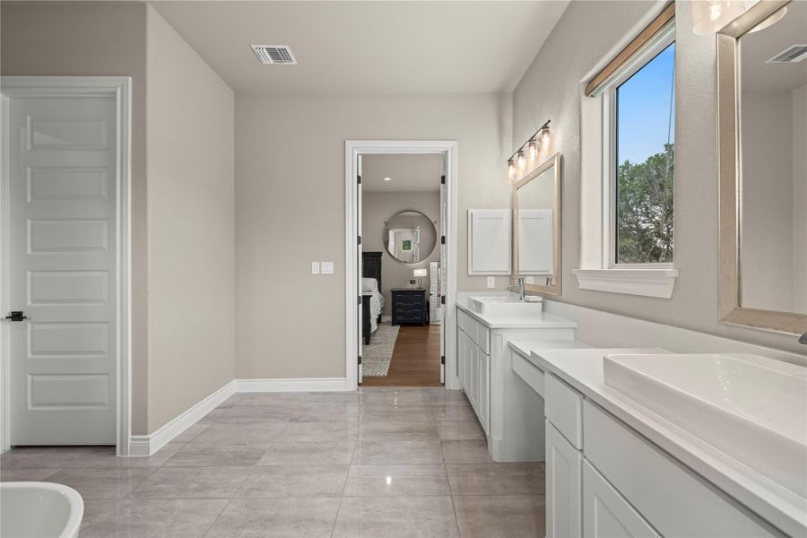 A well-appointed bathroom features dual vanities, modern fixtures, and an inviting view of the adjacent primary bedroom. A well-appointed bathroom features dual vanities, modern fixtures, and an inviting view of the adjacent primary bedroom.
