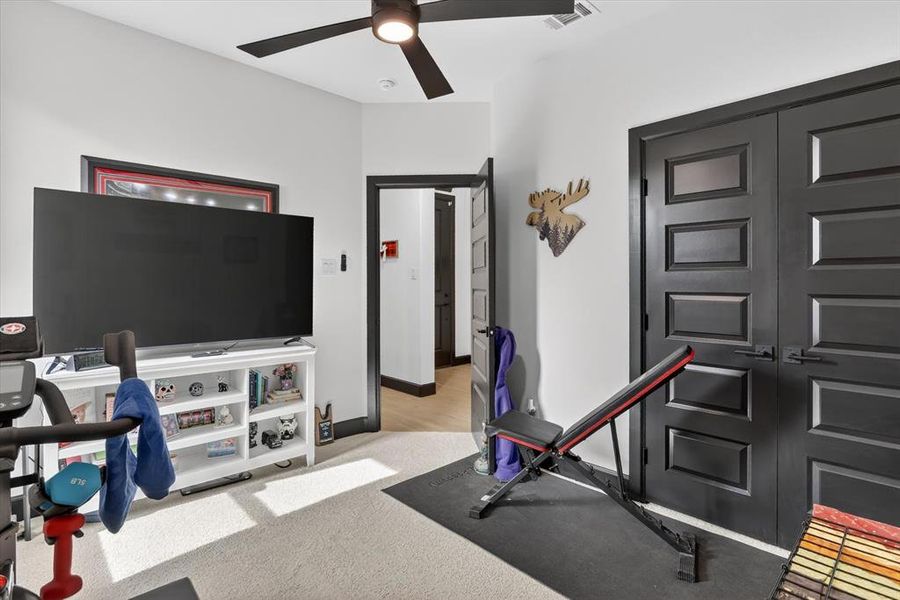 Interior room featuring light-colored carpet, a ceiling fan with integrated lighting, and white walls with contrasting dark trim and doors