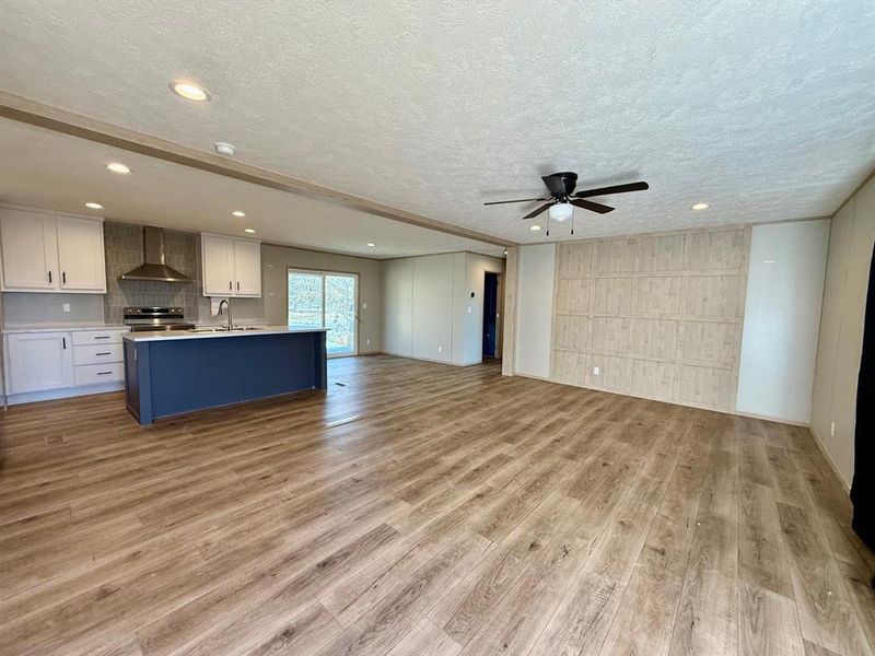 Unfurnished living room featuring a textured ceiling, light wood-style flooring, a ceiling fan, and recessed lighting Unfurnished living room featuring a textured ceiling, light wood-style flooring, a ceiling fan, and recessed lighting
