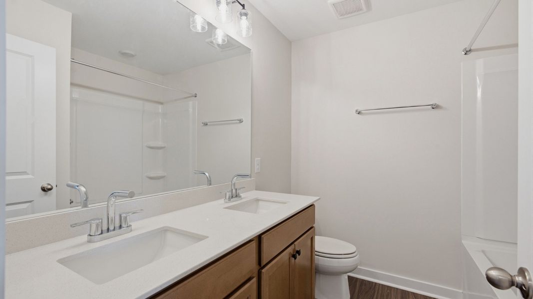 Bathroom with dual vanities across bathtub and shower