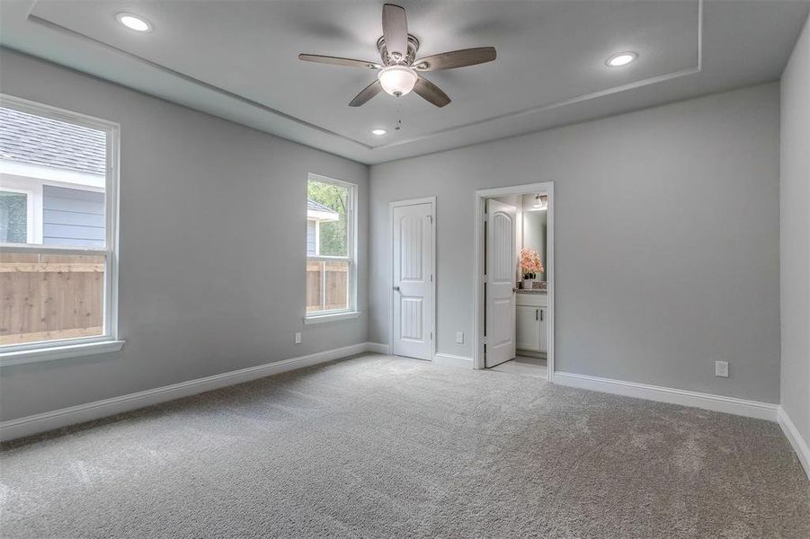 Unfurnished bedroom with ceiling fan, light carpet, and connected bathroom