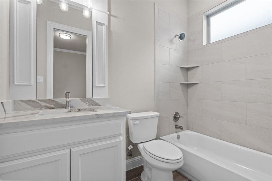 Full bathroom with tiled shower / bath combo, vanity, toilet, and hardwood / wood-style floors.  Not actual home. Previous built example.