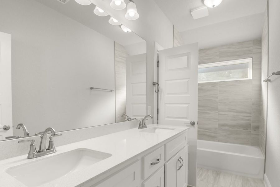 Image of a bathroom with white cabinets and white jack and jill vanity with a large mirror and a shower with tub Image of a bathroom with white cabinets and white jack and jill vanity with a large mirror and a shower with tub