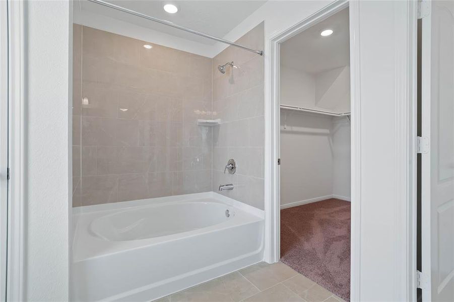 This primary bathroom is definitely move-in ready! Featuring an oversized tub and shower combination with tile surround, stained cabinets with light countertops, high ceilings, neutral paint, sleek and modern finishes.