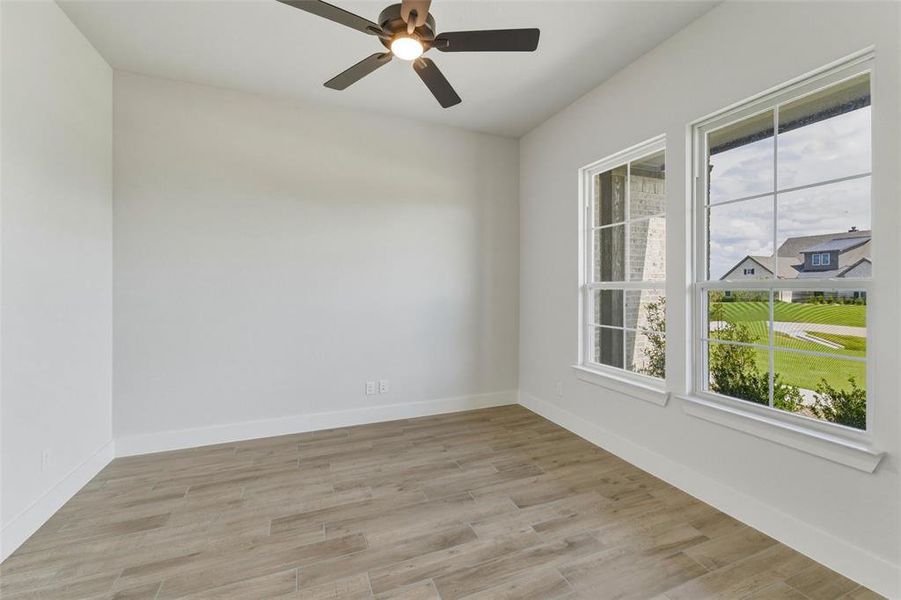 Room featuring wood-finish flooring, white walls, and a ceiling fan with integrated lighting Room featuring wood-finish flooring, white walls, and a ceiling fan with integrated lighting