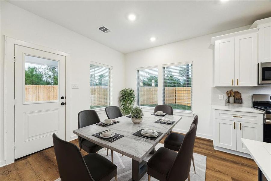 Enjoy meals in this bright and inviting dining area, where large windows provide a serene view of the backyard. The open layout creates a seamless transition from the kitchen, making it easy to host gatherings or enjoy quiet family dinners in this thoughtfully designed space.