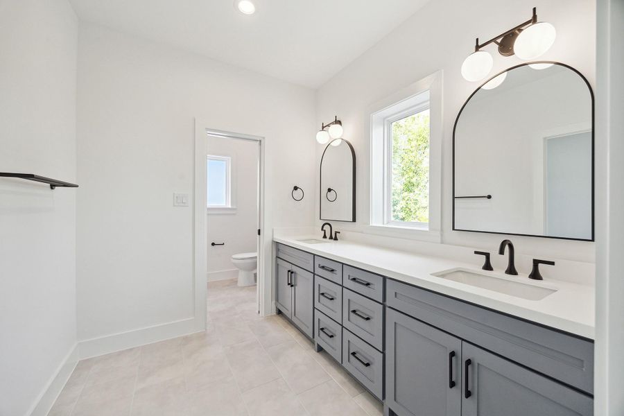 Jack and Jill full bath accessible from both bedrooms with tub/shower combination, classic tiles, dual vanities, decorative fixtures and large casement window inviting natural light
