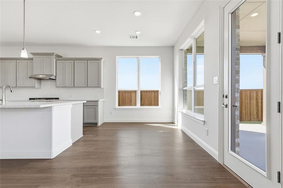 Kitchen with gray cabinets, recessed lighting, hanging light fixtures, dark wood finished floors, and tasteful backsplash Kitchen with gray cabinets, recessed lighting, hanging light fixtures, dark wood finished floors, and tasteful backsplash
