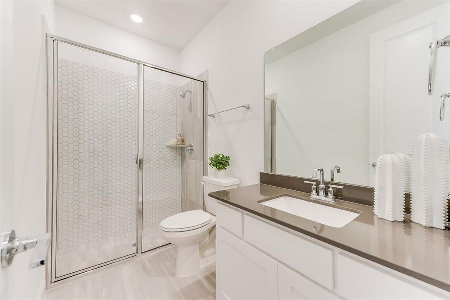 Bathroom featuring toilet, vanity, and a shower with shower door