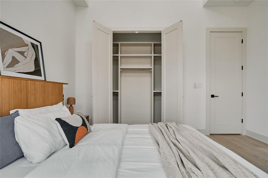 Bedroom featuring light wood-finish flooring and a built-in closet with bifold doors