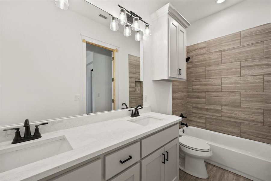 Full bathroom with hardwood / wood-style floors, vanity, toilet, and tiled shower / bath