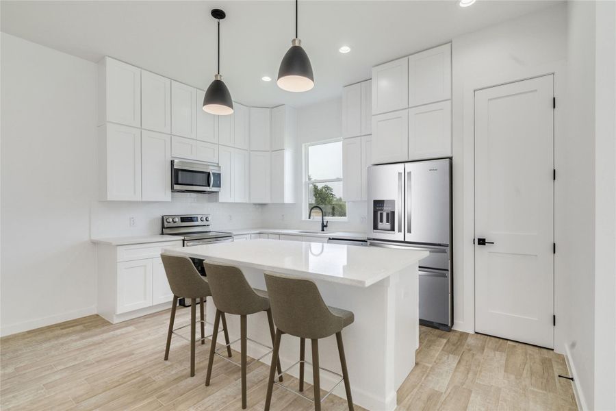 Modern kitchen with white cabinetry, stainless steel appliances, and a central island. Modern kitchen with white cabinetry, stainless steel appliances, and a central island.