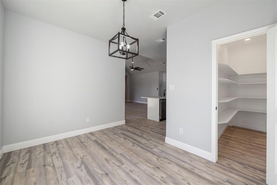 Unfurnished dining area featuring a chandelier and light wood-style floors Unfurnished dining area featuring a chandelier and light wood-style floors