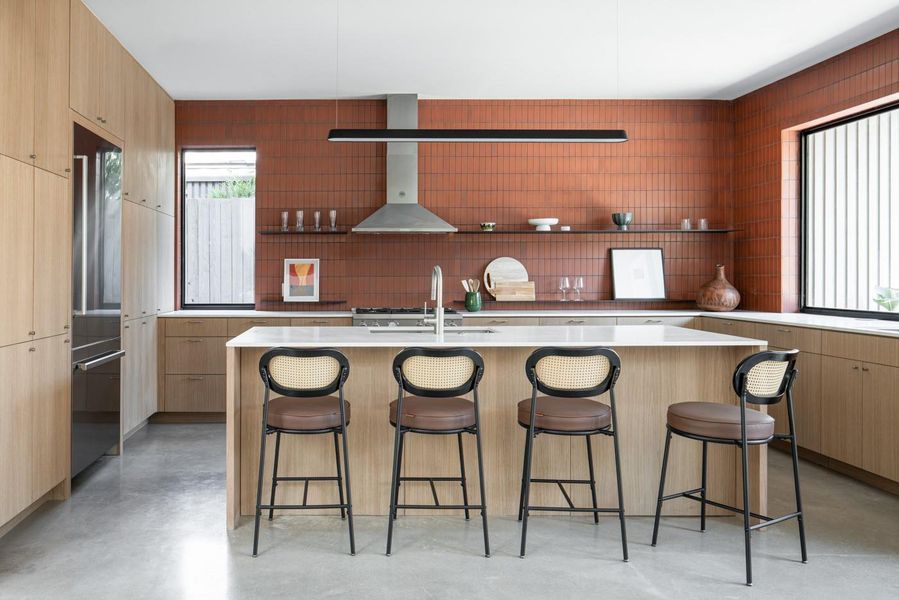 Kitchen featuring a breakfast bar area, open shelves, finished concrete flooring, modern cabinets, and high end refrigerator