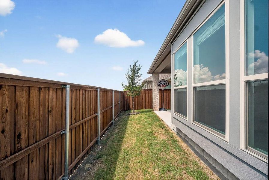 Private side yard with a full wood fence, concrete walkway, and grassy area