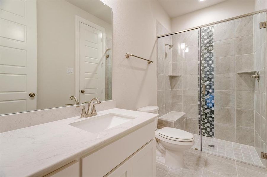 Bathroom featuring a shower with shower door, tile patterned flooring, toilet, and vanity