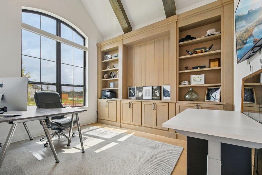 This room features a large arched window with black framing, a built-in wooden shelving unit with cabinets, and exposed ceiling beams This room features a large arched window with black framing, a built-in wooden shelving unit with cabinets, and exposed ceiling beams