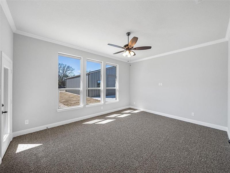 Prior listing photo. Property remains accurate - Unfurnished room featuring ceiling fan, dark colored carpet, and crown molding