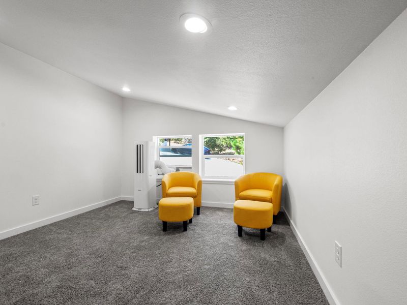 Carpeted room featuring a white vaulted ceiling with recessed lighting and multiple windows