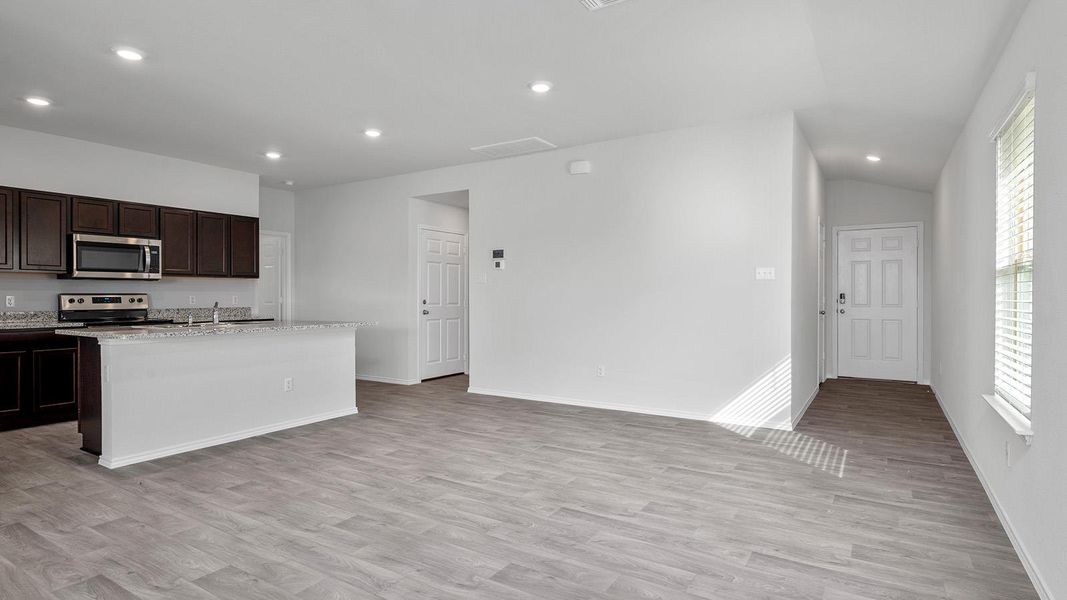 Kitchen featuring dark wood finish cabinetry, recessed lighting, a kitchen island with sink, light stone countertops, and stainless steel appliances