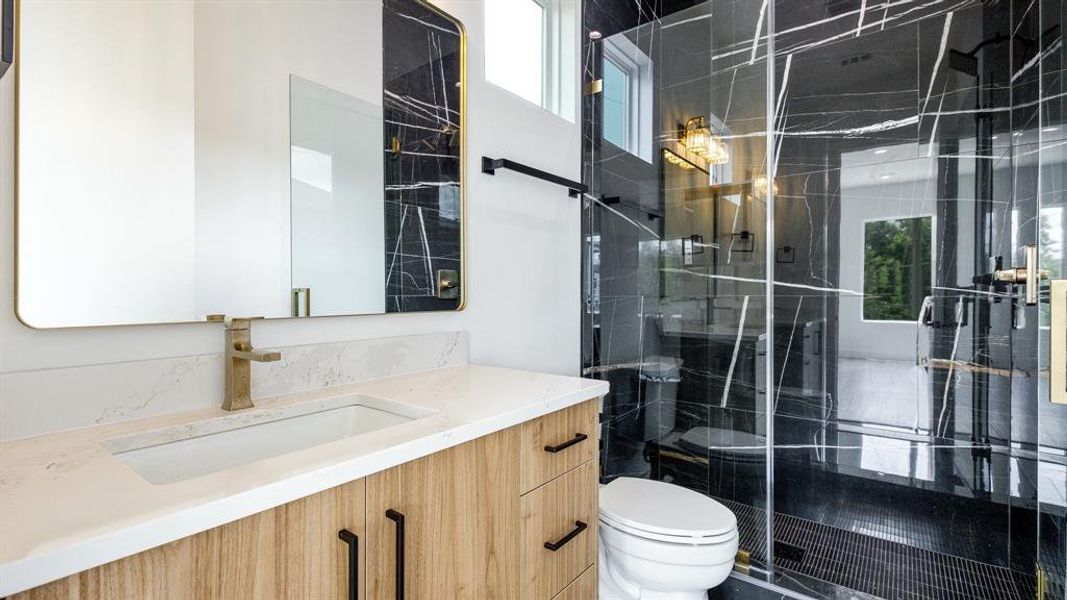 Bathroom with a shower with door, vanity, and toilet