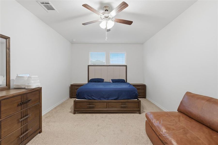 Spacious room featuring vaulted ceilings, neutral-toned carpeting, two windows with blinds, and a ceiling fan with light fixture