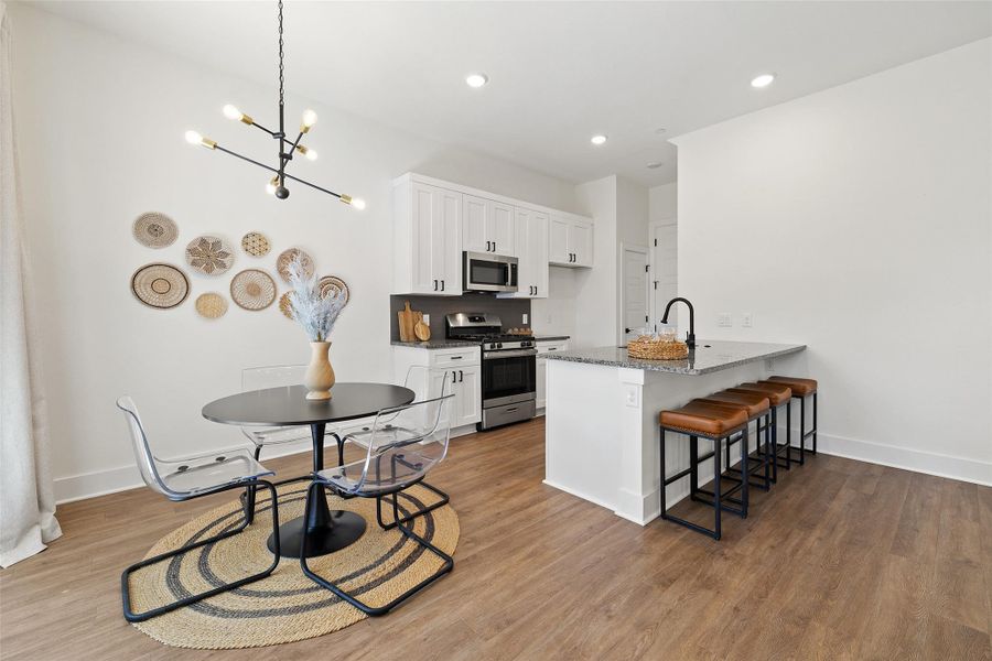 Kitchen featuring a breakfast bar, appliances with stainless steel finishes, white cabinets, dark stone counters, and a peninsula Kitchen featuring a breakfast bar, appliances with stainless steel finishes, white cabinets, dark stone counters, and a peninsula