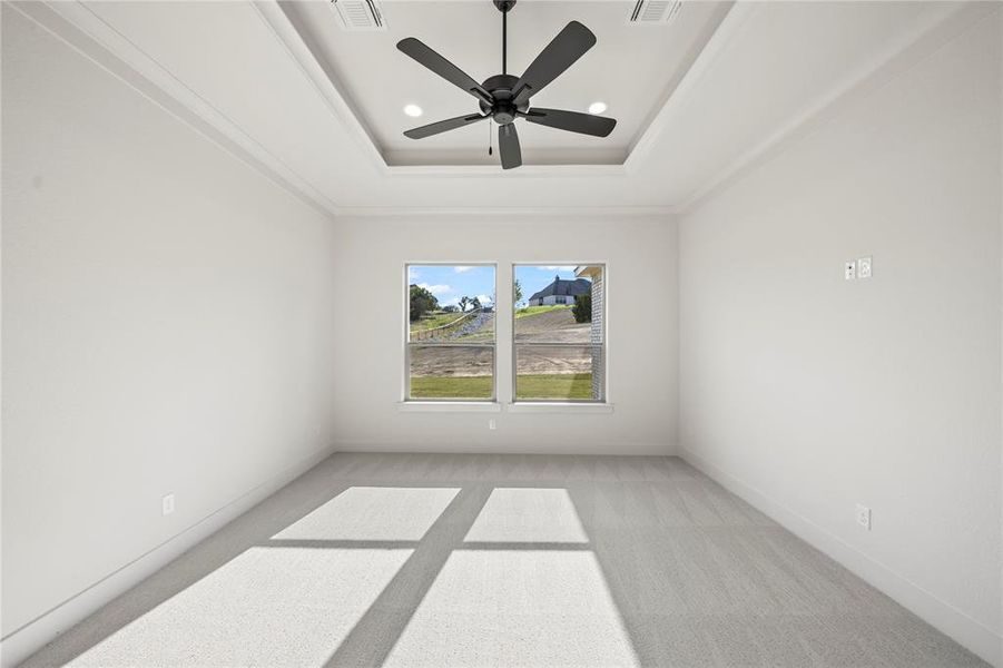 Spare room featuring a tray ceiling, light colored carpet, recessed lighting, and a ceiling fan